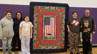 People standing with a quilt.