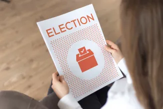Person holding a booklet titled "Election"