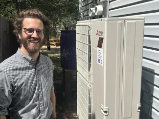 Man standing next to an air-source heat pump.