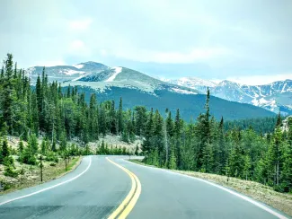 Winding two lane road in the foreground with Mount Blue Sky (formerly Mount Evans) Colorado in the backgrount