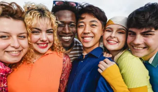 Diverse group of six young people standing close together smiling