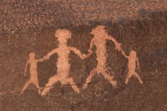 Rock petroglyph representing two adults and two children holding hands