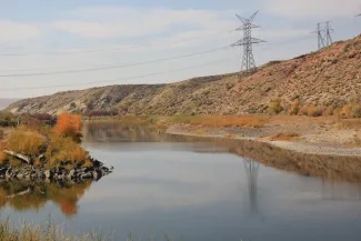 Transmission line and Yampa River - Allen Best - Big Pivots High voltage power transmission towers and lines spanning a river.