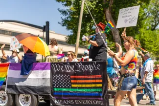 People marching in a pride parade with various flags and symbols.