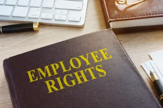 Book titled "Employee Rights" on a desk near pens, a computer keyboard, and another book