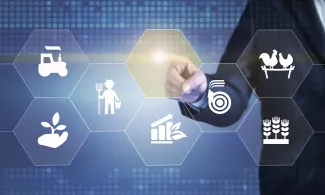 PROMO HIRES Agriculture - Generic Symbols Finger Point - iStock - denizbayram Person dressed in a suit pointing towards agriculture symbols in the foreground.