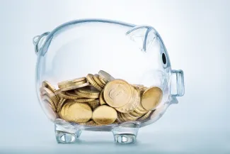 PROMO HIRES Finance - Glass Piggy Bank with Coins - Pogonici - iStock Glass piggy bank half filled with gold coins