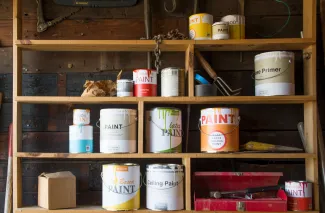 Various sizes of paint cans on wooden shelves.