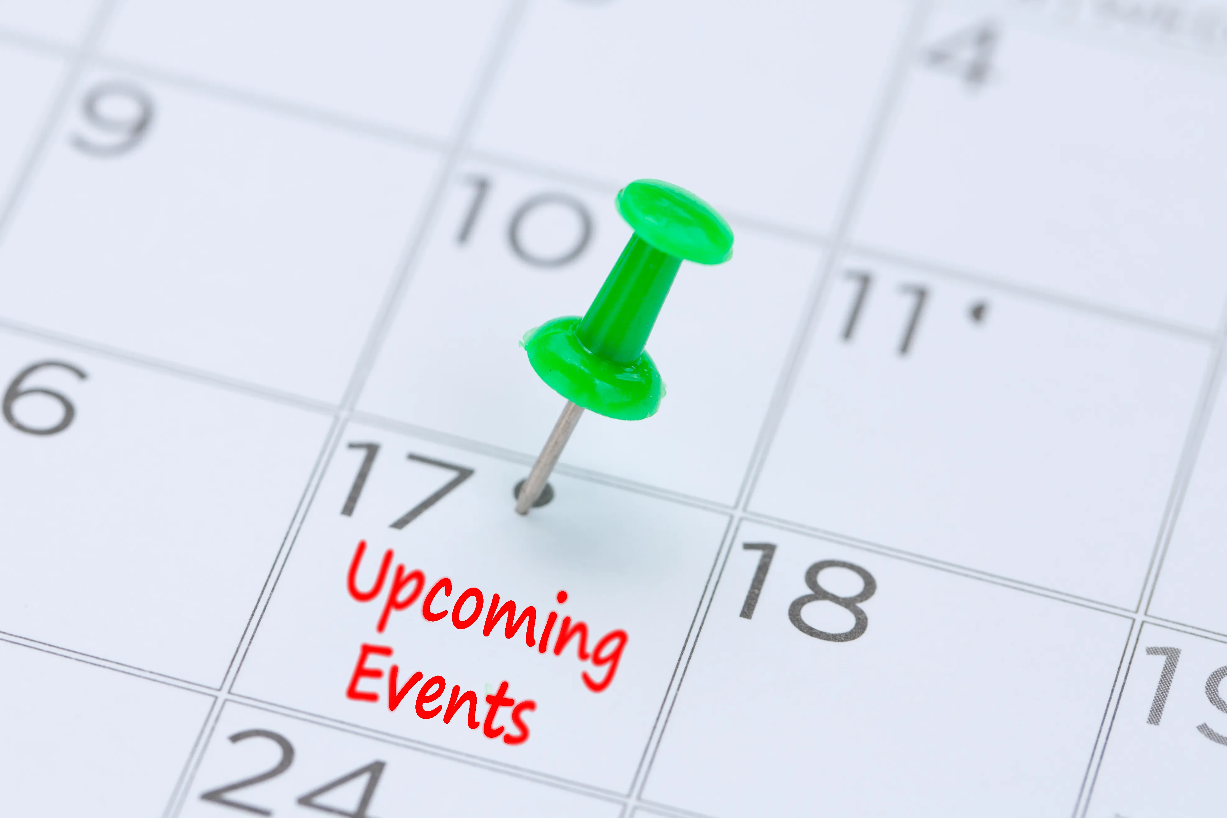 Closeup of a calendar with a pushpin in a date with the words "Upcoming Events"