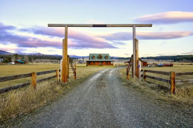 The gated entry at a beautiful, expansive ranch. There is a wood-built custom house on the property.