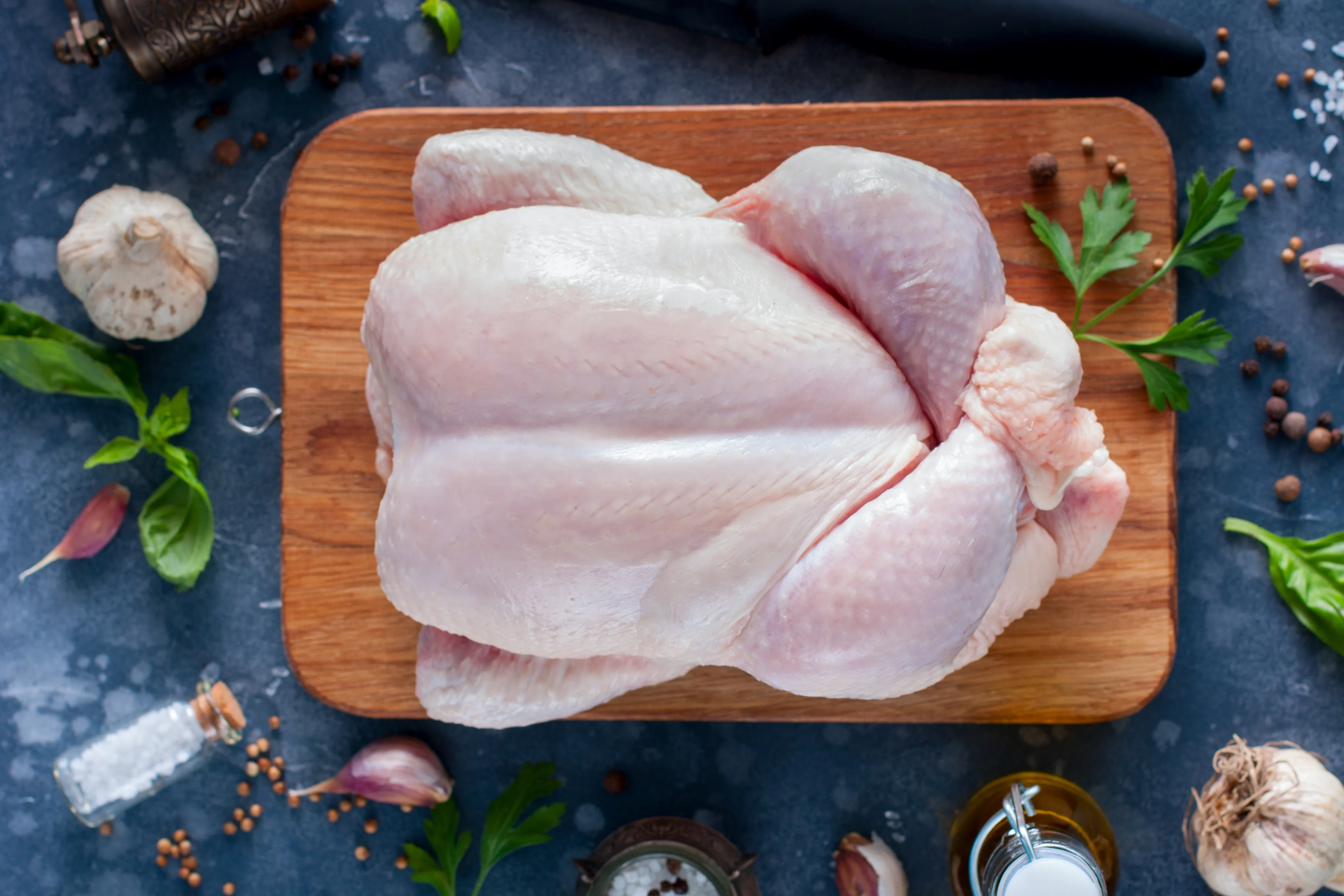 Overhead view of a raw turkey on a food preparation board surround by herbs and spices