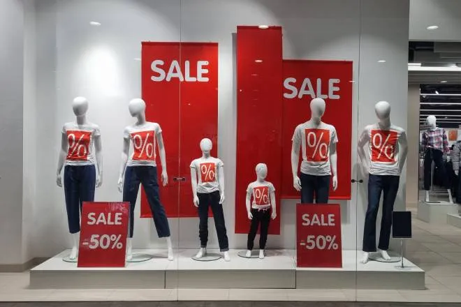 Manequins in white shirts with a red box with % signs in them surrounded by sale signs that advertise 50% off.