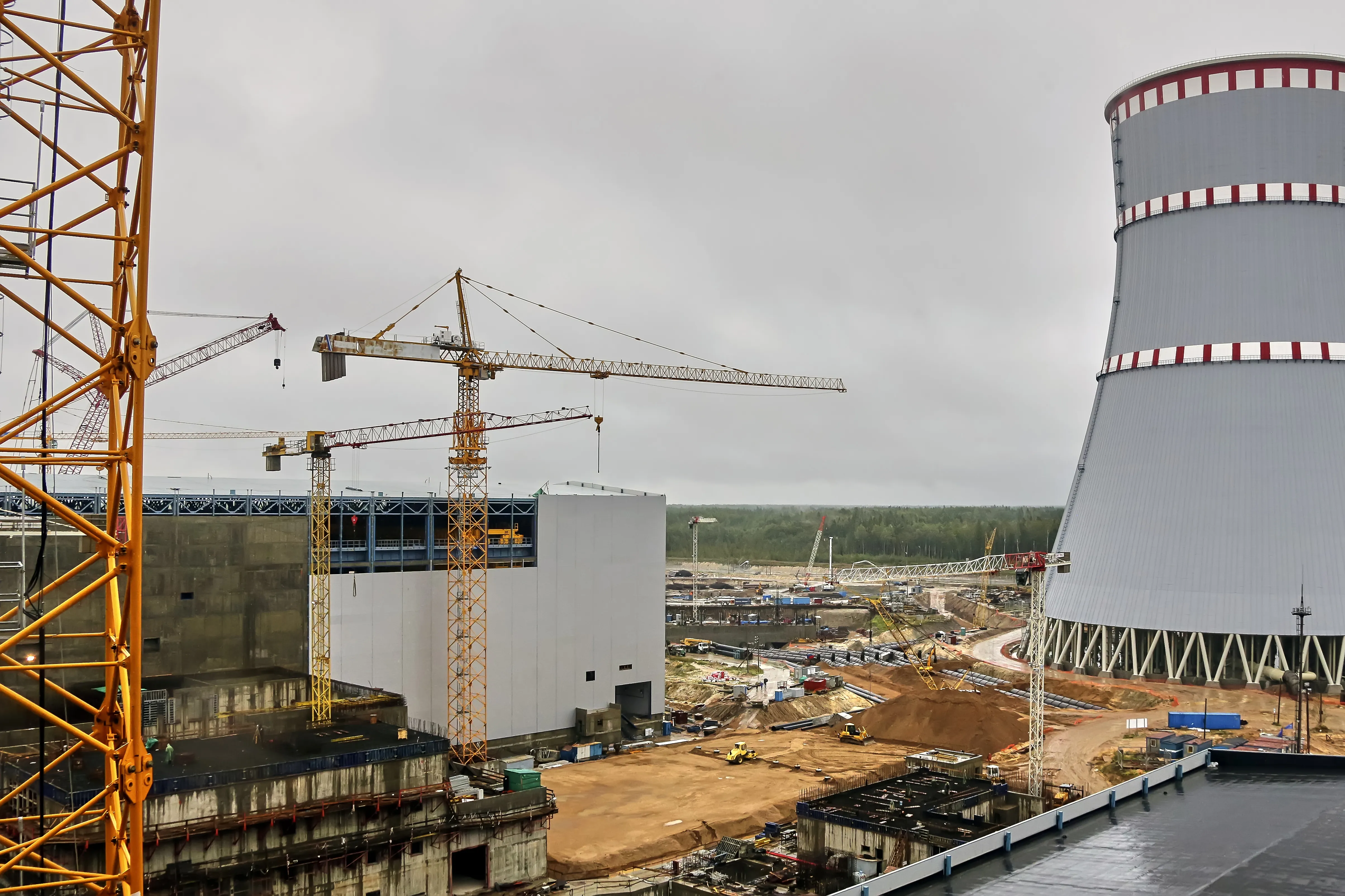 Construction cranes around a nuclear power plant and cooling tower