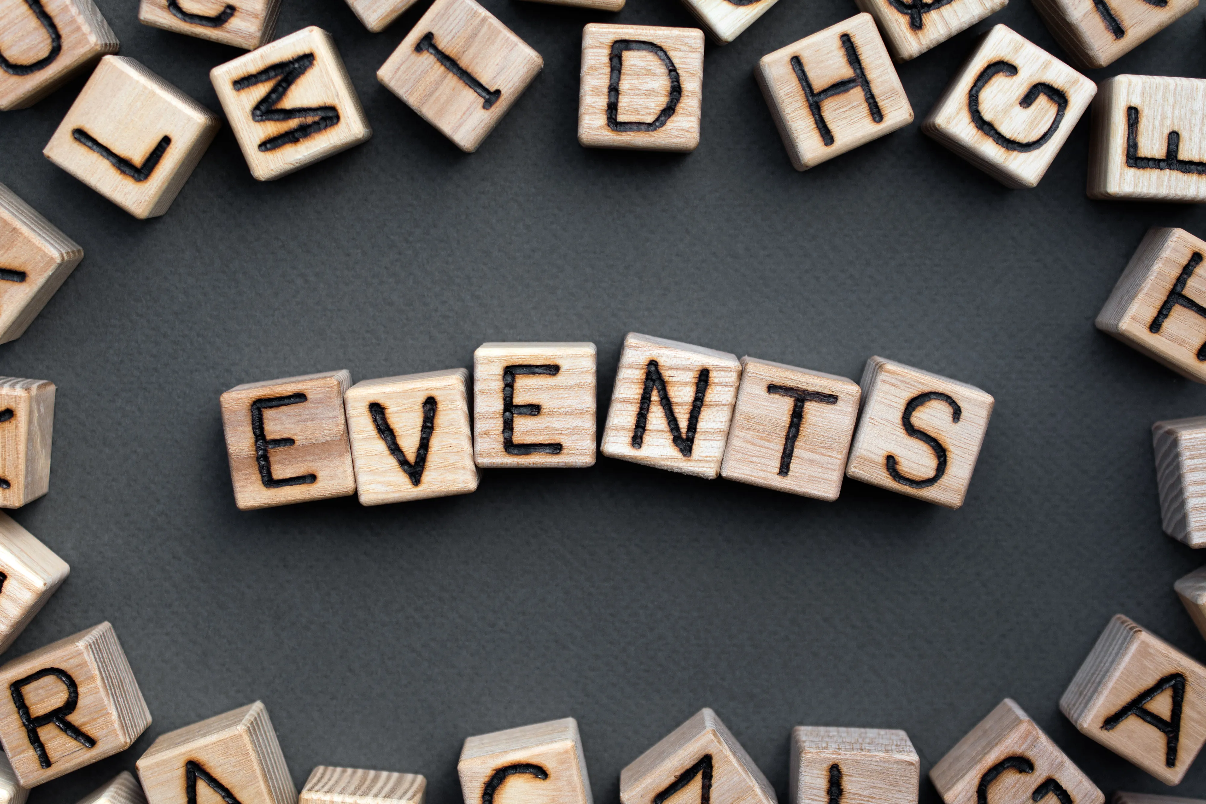 Assorted wooden block with letters on the sides, surrounding the word "events" on wooden blocks