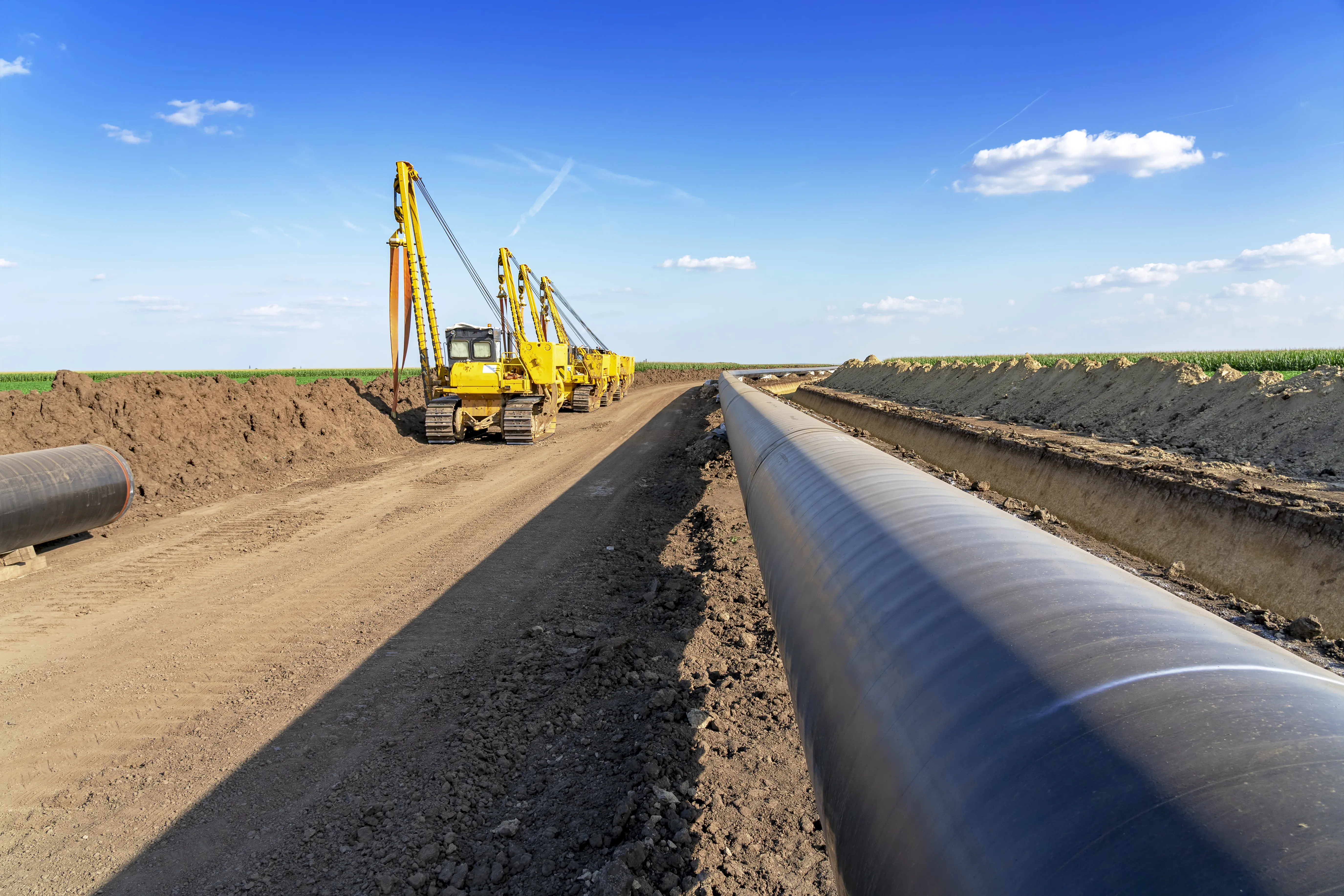 Pipeline being buried with heavy equipment in the background.
