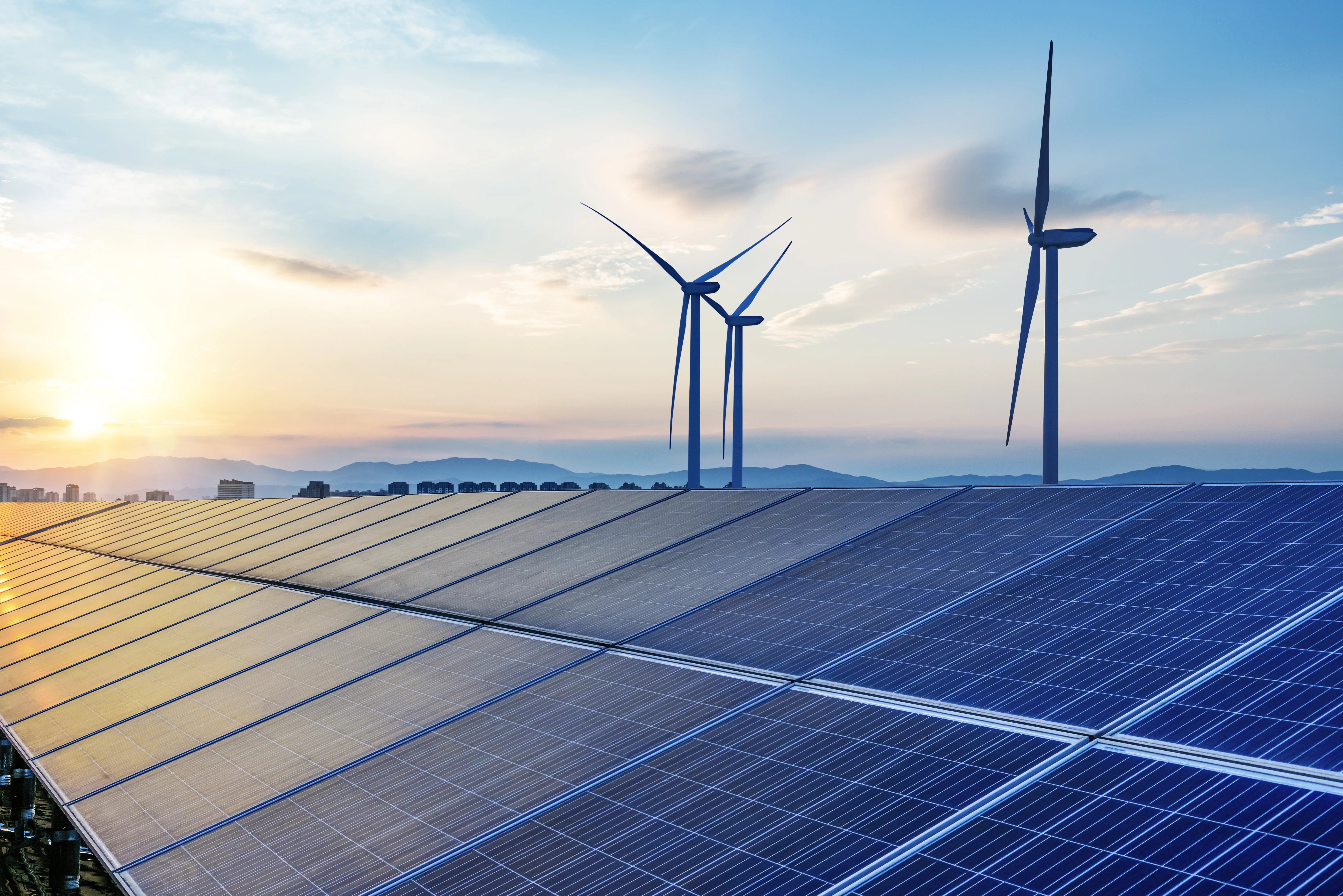 Solar panels with wind turbines in the background.