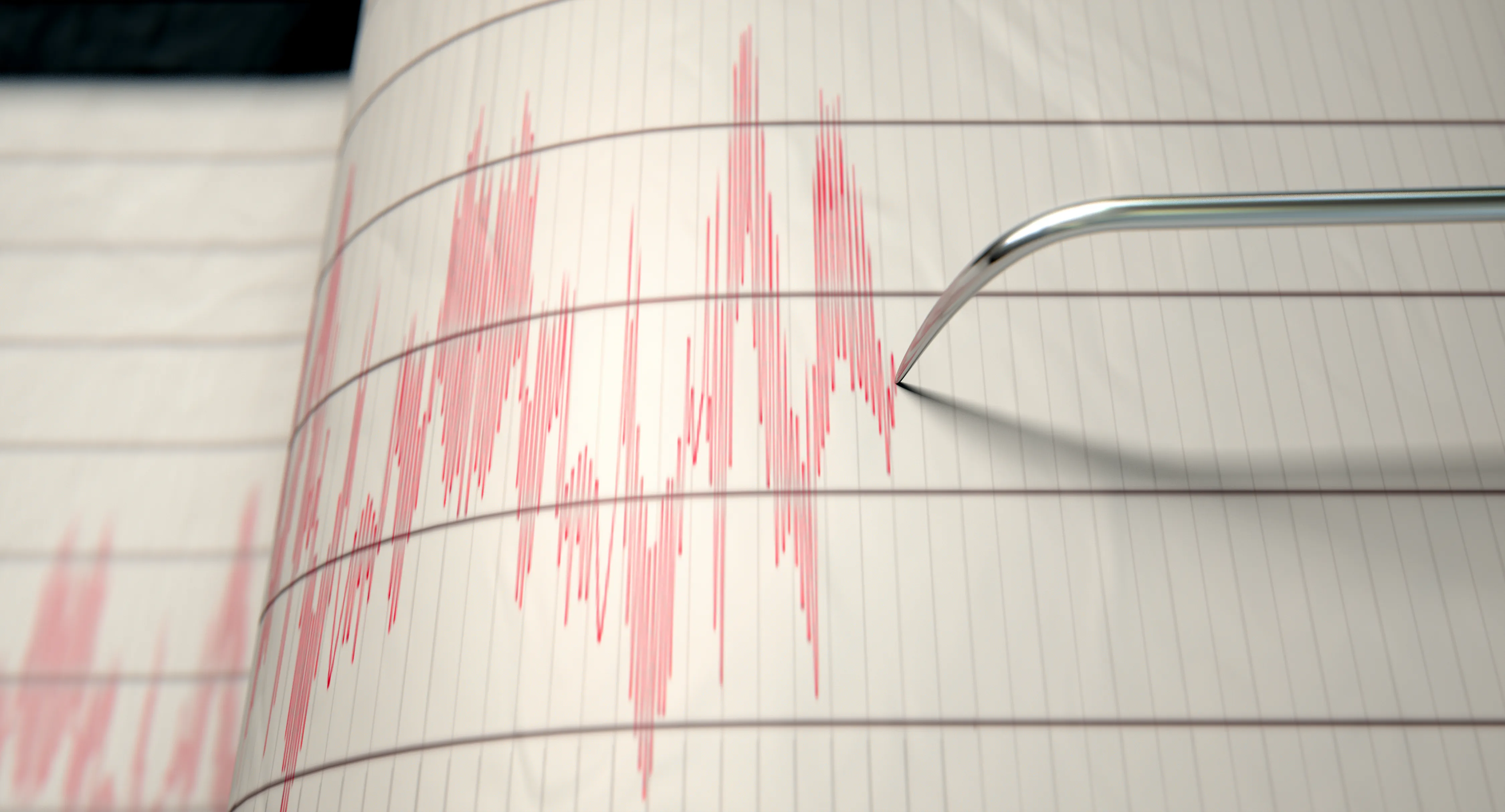 Earthquake seismograph paper with a stylus pen recording large activity variations.