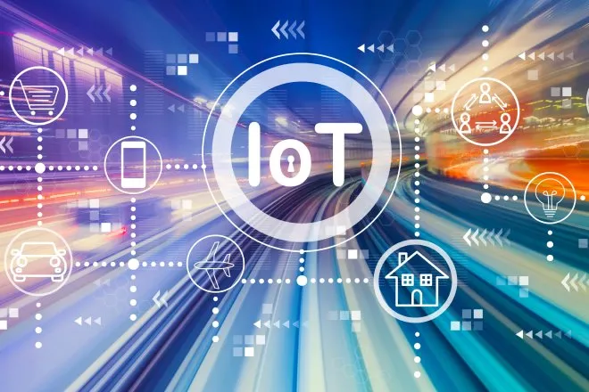 A blurred road with colorful lighting and a superimposed graphic of different IoT symbols and the acronym "IoT" in the middle.