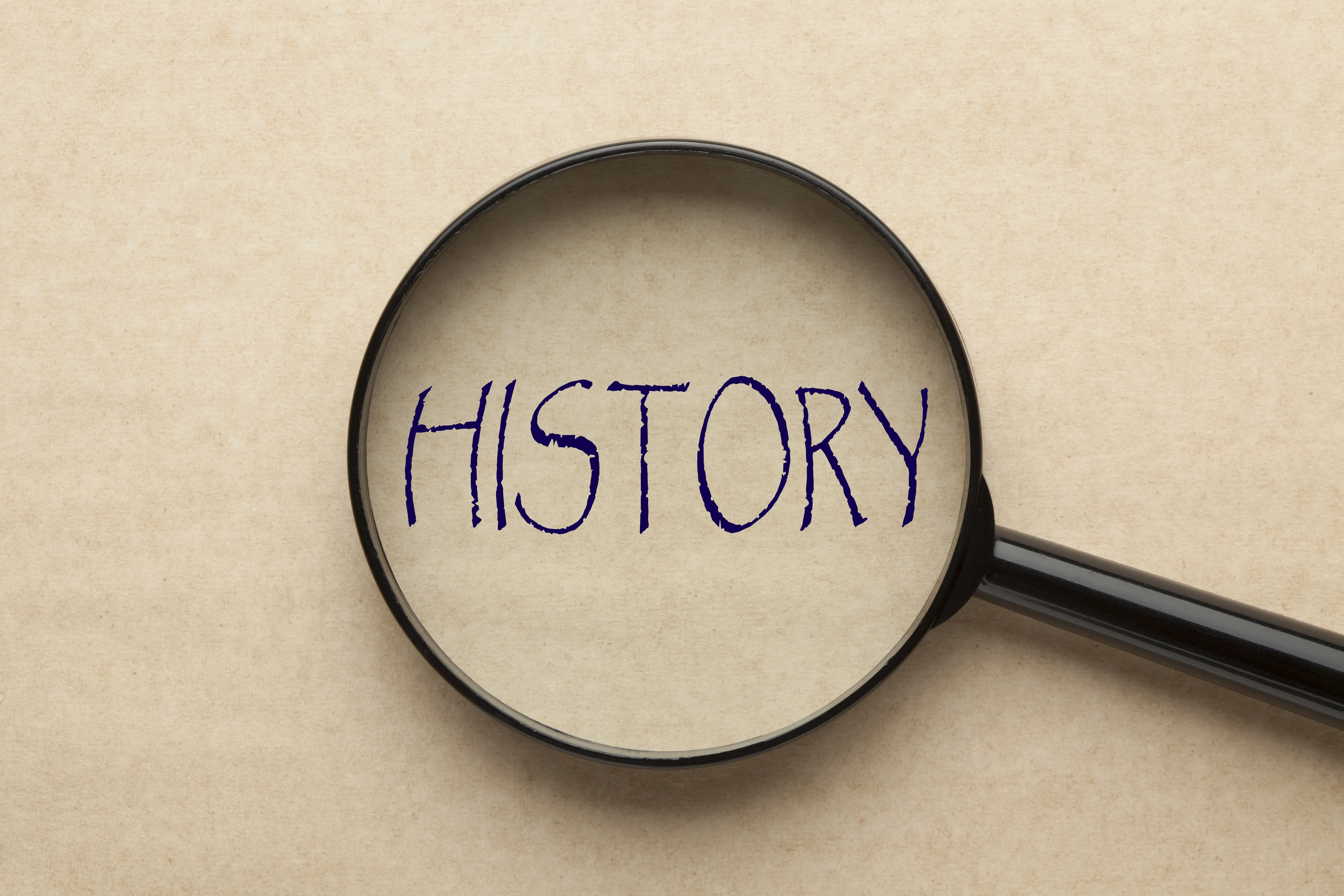 Overhead view of a magnifying glass over the word "history."