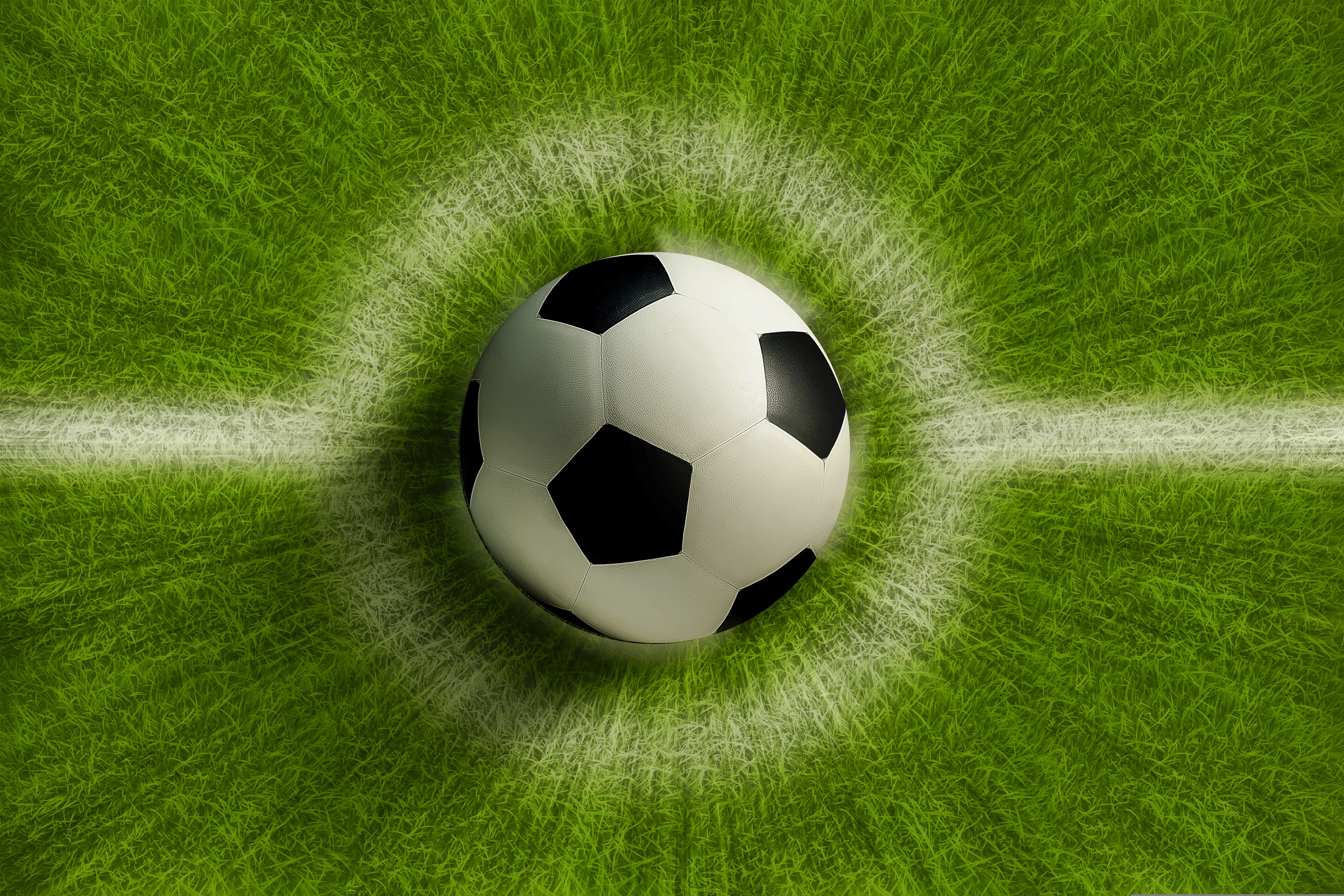 Overhead view of a soccer ball/football on a grassy background with a chalk outline.