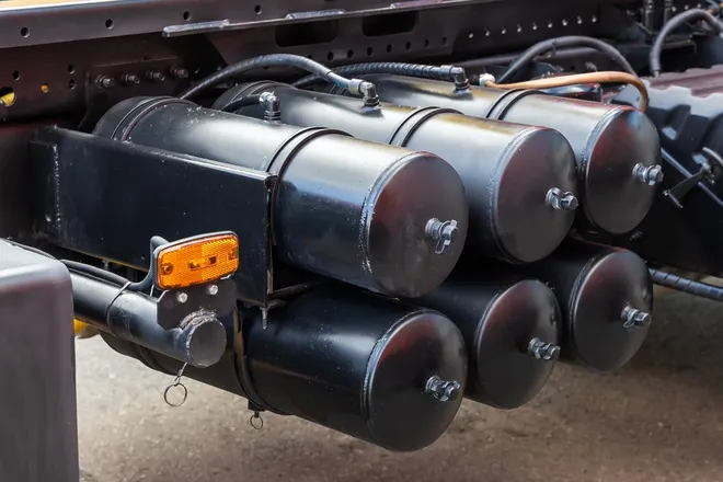 Six air cylinder tanks in a brake system are at close range. They're situated underneath a heavy-duty truck.