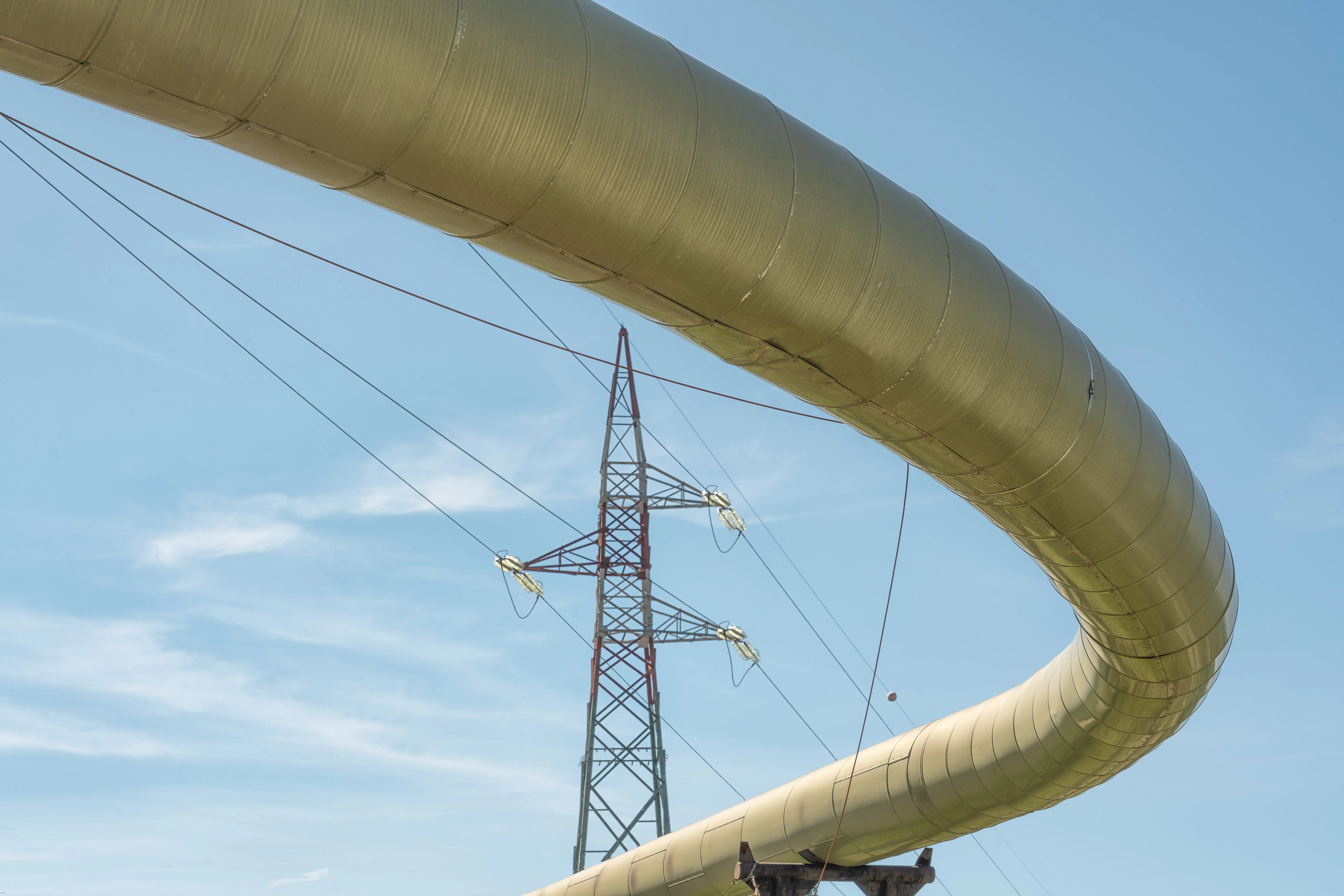 Pipeline representing geothermal energy with a high voltage power line in the background.