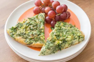 Small stack of plates with two slices of spinach frittata and a small group of grapes.