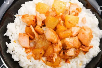 Plate of pineapple chicken on a bed of rice.