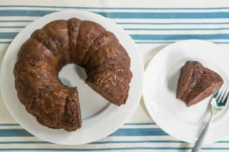 Plate of chocolate squash cake with a slice removed, which has been placed on a separate plate with a fork.