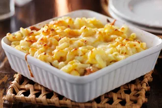 Baking dish of macaroni and cheese on a woven mat.