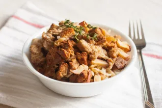 Bowl of stuffing on a cloth next to a fork.