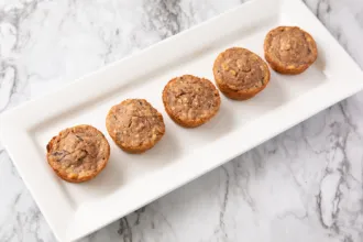 Rectangular plate on a marble surface containing 5 wild rice muffins