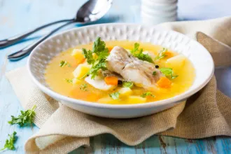 Bowl of walleye chowder on a cloth next to a spoon