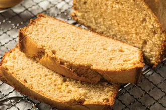 Loaf of three-grain peanut bread on a cooling rack with two pieces sliced off.