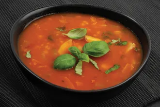 Bowl of lentil barley soup with fresh oregano leaves as a garnish