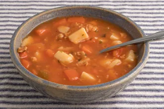 Bowl of Manhattan clam chowder with a spoon resting inside