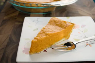 Slice of mock souther sweet potato pie on a square plate with a fork.