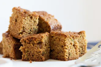 Pineapple Zucchini Cake - USDA Stack of cut pineapple zucchini cake squares. A serving spatula is blurred in the foreground.