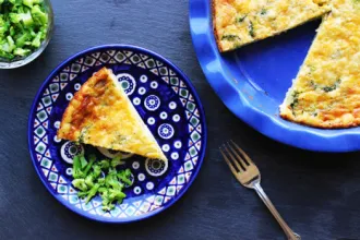 Magic Crust Quiche - USDA Pie pan with a Magic Crust Quiche. A slice has been removed and set on a nearby serving plate with a small amount of broccoli.