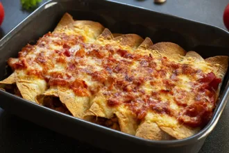 Baking pan containing four bean and rice burritos with salsa.