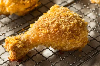 A leg of crispy oven-fried chicken resting on a wire cooling rack.